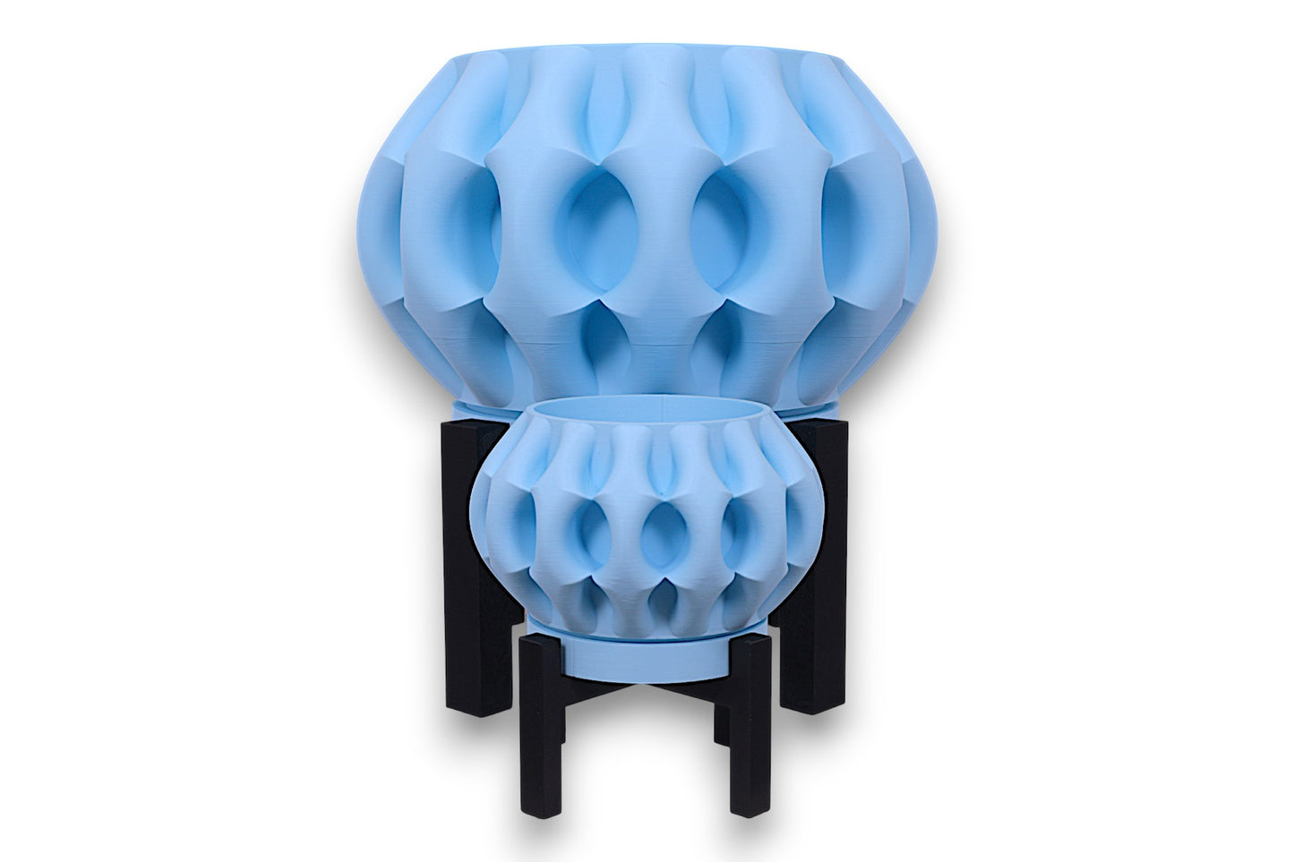 Two light blue PLA planters – 3D printed with oval dimple textures and rounded forms, displayed on black four-legged stands
