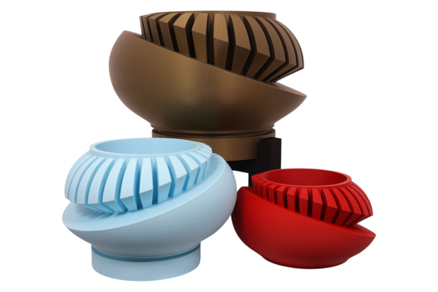 Bronze, light blue, and red PLA sculptures – 3D printed with interlocking spiral blade textures, displayed together on black stands in staggered heights

