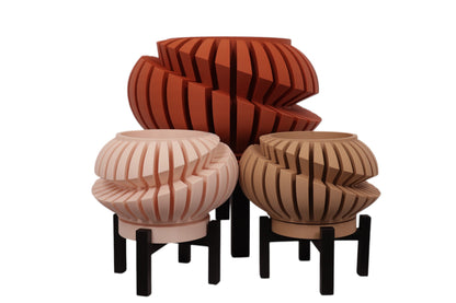 Beige, terracotta, and tan PLA planters – 3D printed with spiral slat textures, shown together on black stands in staggered heights

