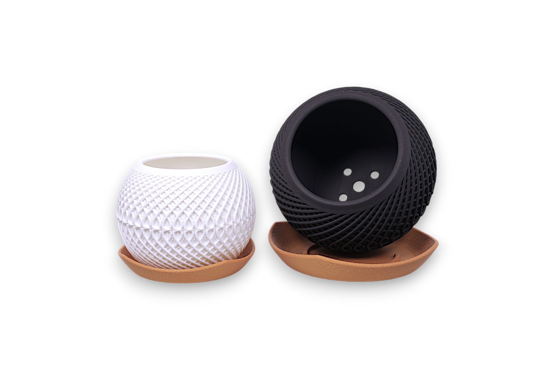 Spherical white and black PLA planters – 3D printed with geometric textures, each placed on shallow brown tray
