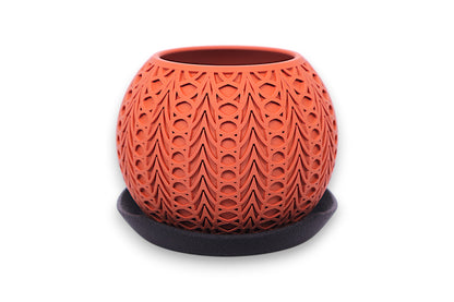 Terracotta PLA planter – 3D printed with symmetrical teardrop and oval cutouts, displayed on dark saucer
