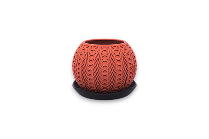 Terracotta PLA planter – 3D printed with symmetrical teardrop and oval cutouts, displayed on dark saucer
