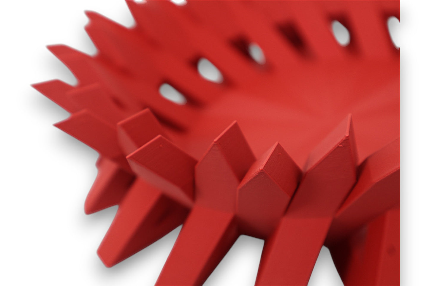 Close up Red catch-all tray with jagged vertical spikes and smooth concave center