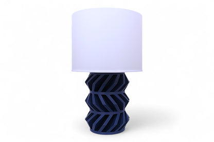 Table lamp – white pleated lampshade with dark blue sculptural base, angular gear-like design
