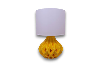 Table lamp – white cylindrical lampshade with sculptural yellow bulbous base, geometric interwoven pattern
