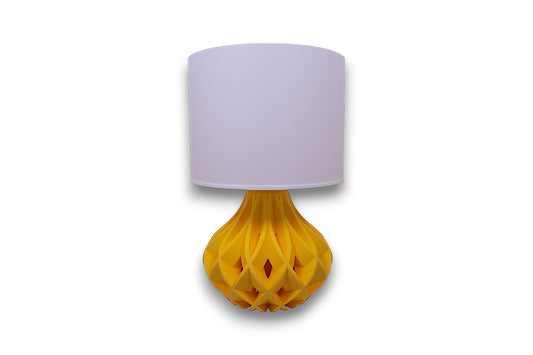 Table lamp – white cylindrical lampshade with sculptural yellow bulbous base, geometric interwoven pattern
