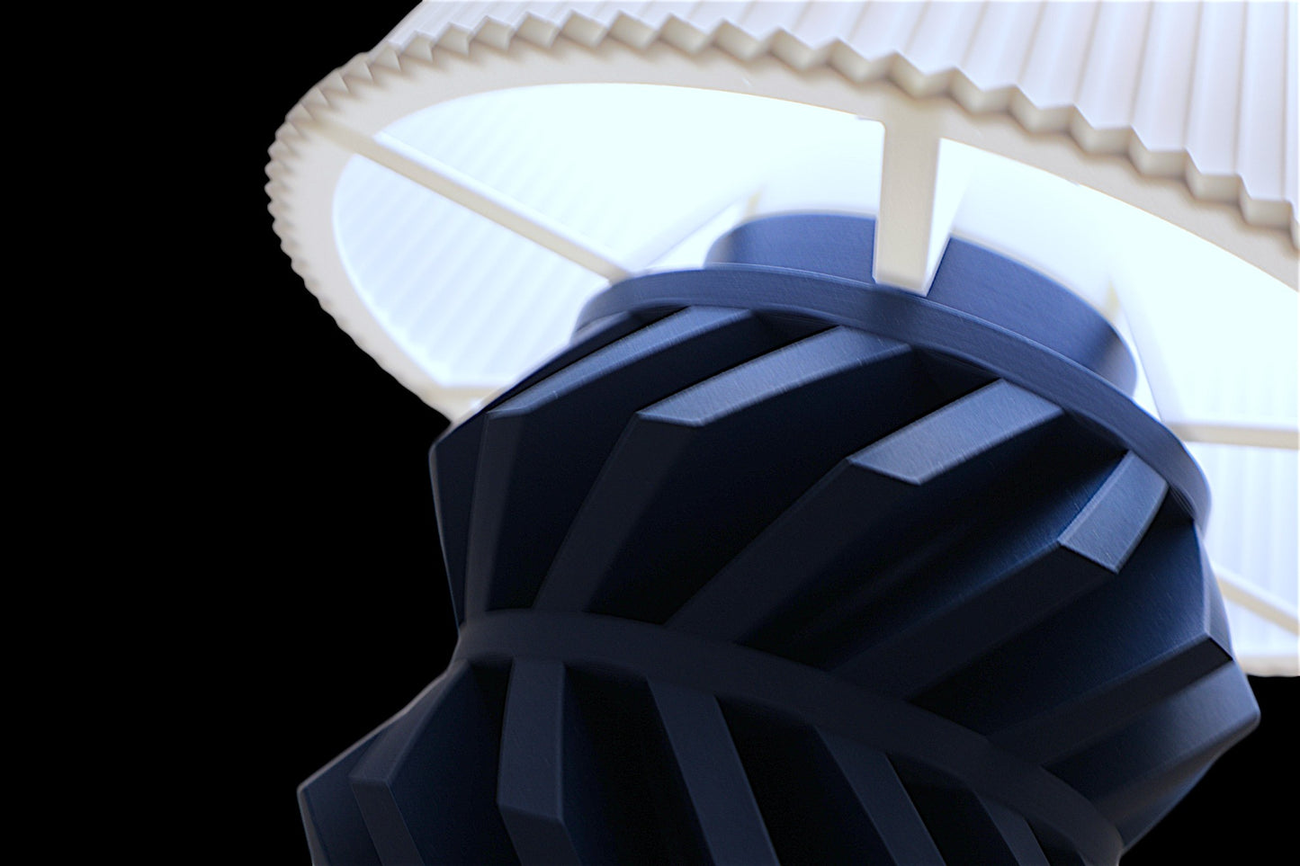 Table lamp – white ribbed lampshade with dark geometric base, shown from below against black background

