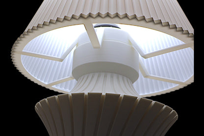 Close-up of a white light fixture with a ribbed design on a black background