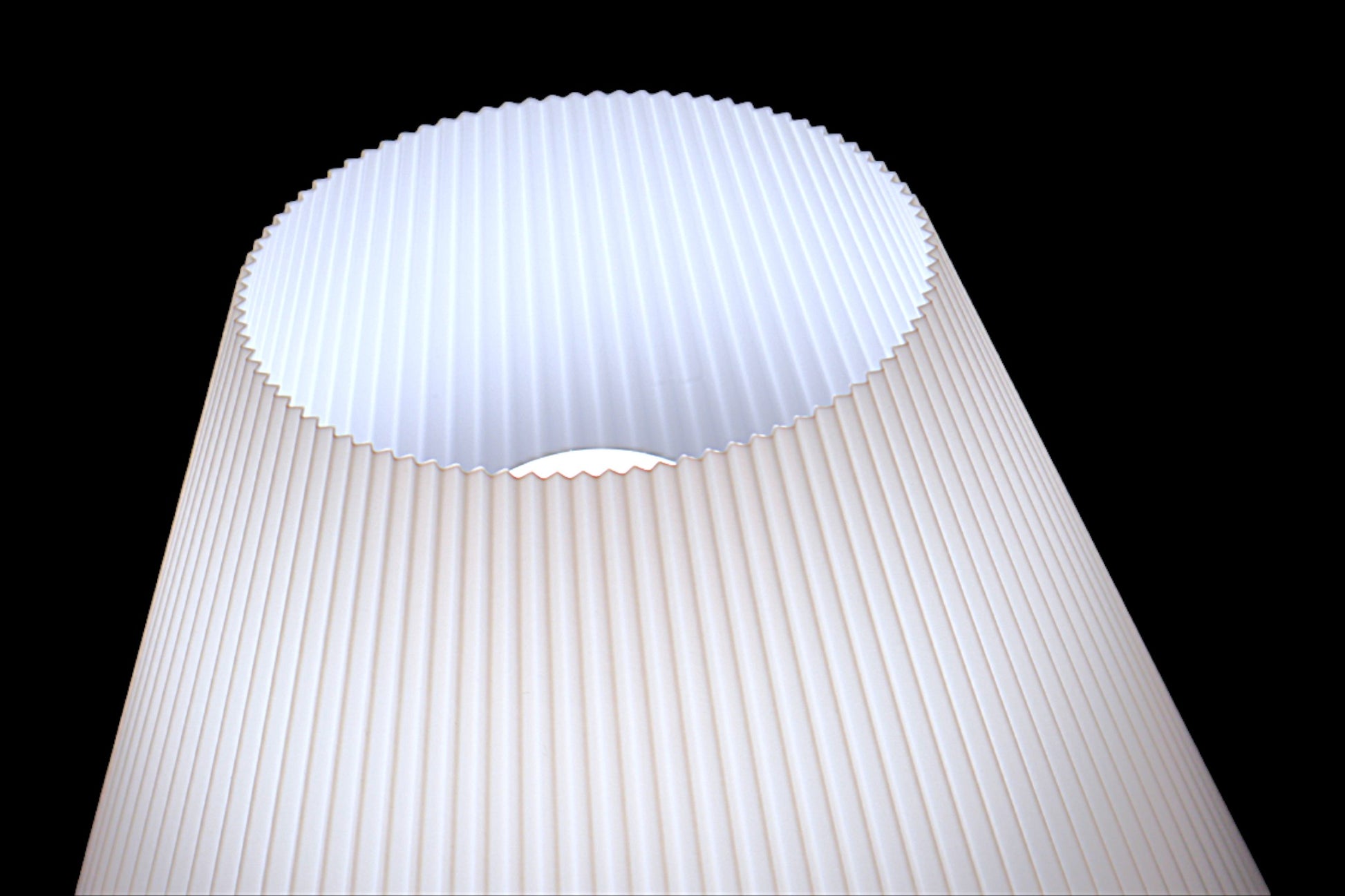 White lampshade with pleated design on a black background