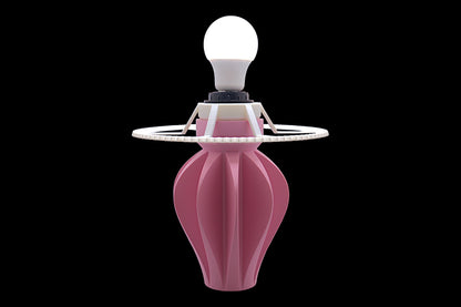 Table lamp – white cylindrical lampshade with sculptural pink fluted base, shown against black background
