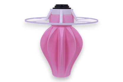 Table lamp – white cylindrical lampshade with sculptural pink fluted base, shown against black background
