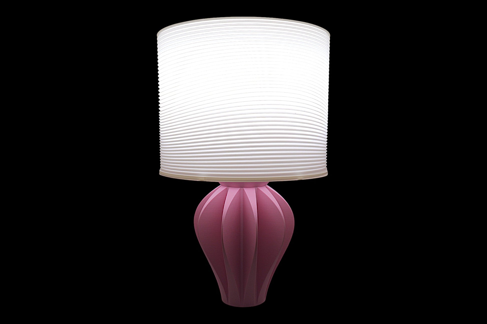 Pink table lamp with a white lampshade on a black background
