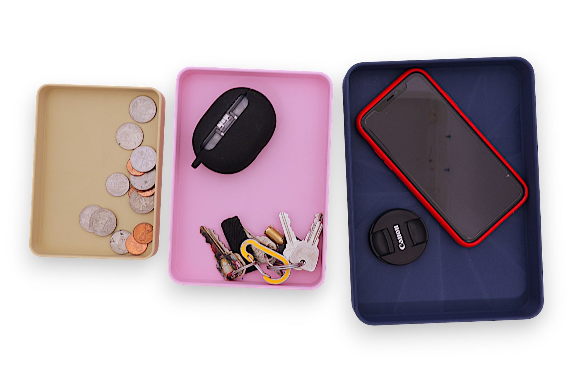 Three trays with various items including coins, keys, and a phone on a white background