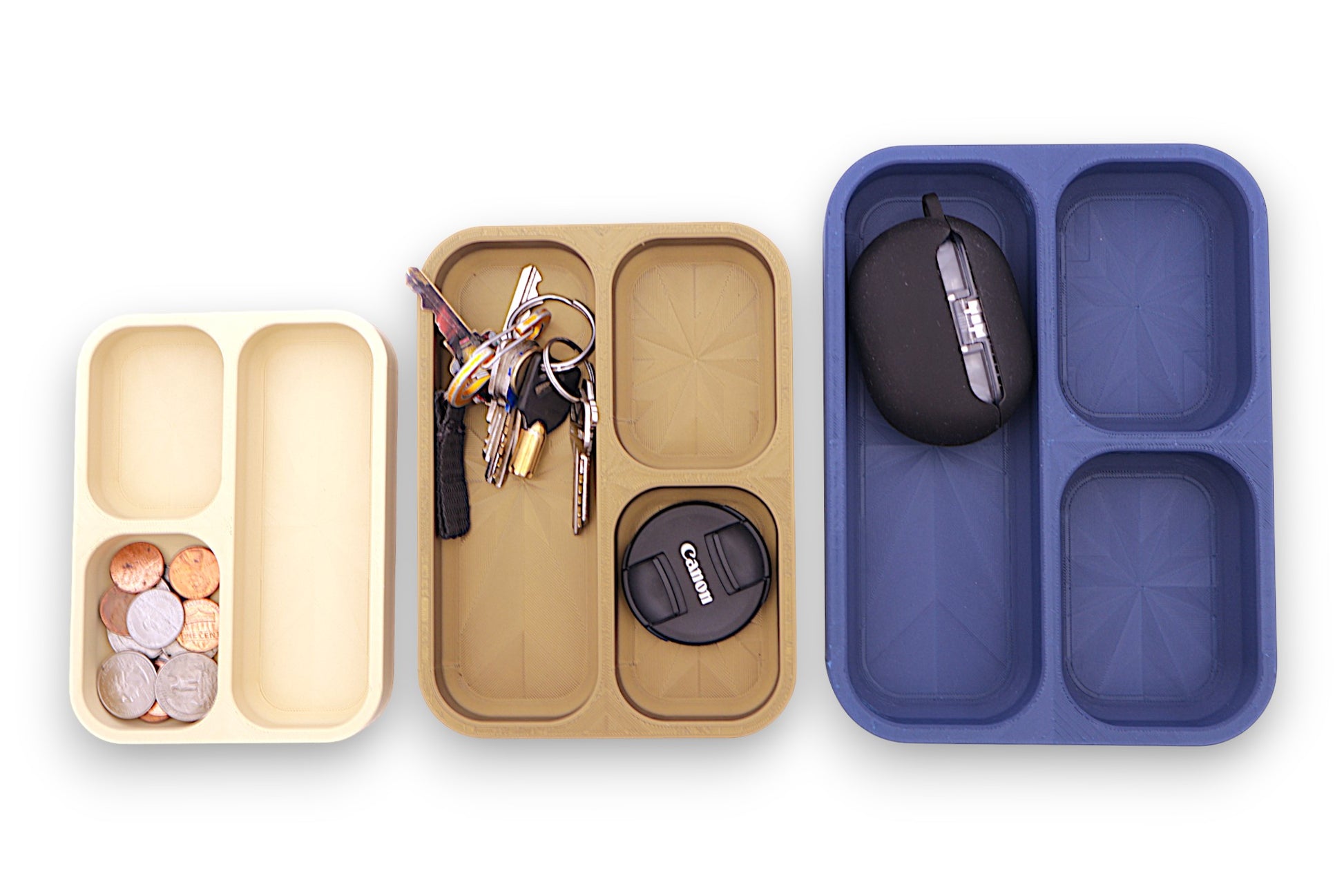 Three compartments of a organizer with items including keys, coins, and earbuds on a white background