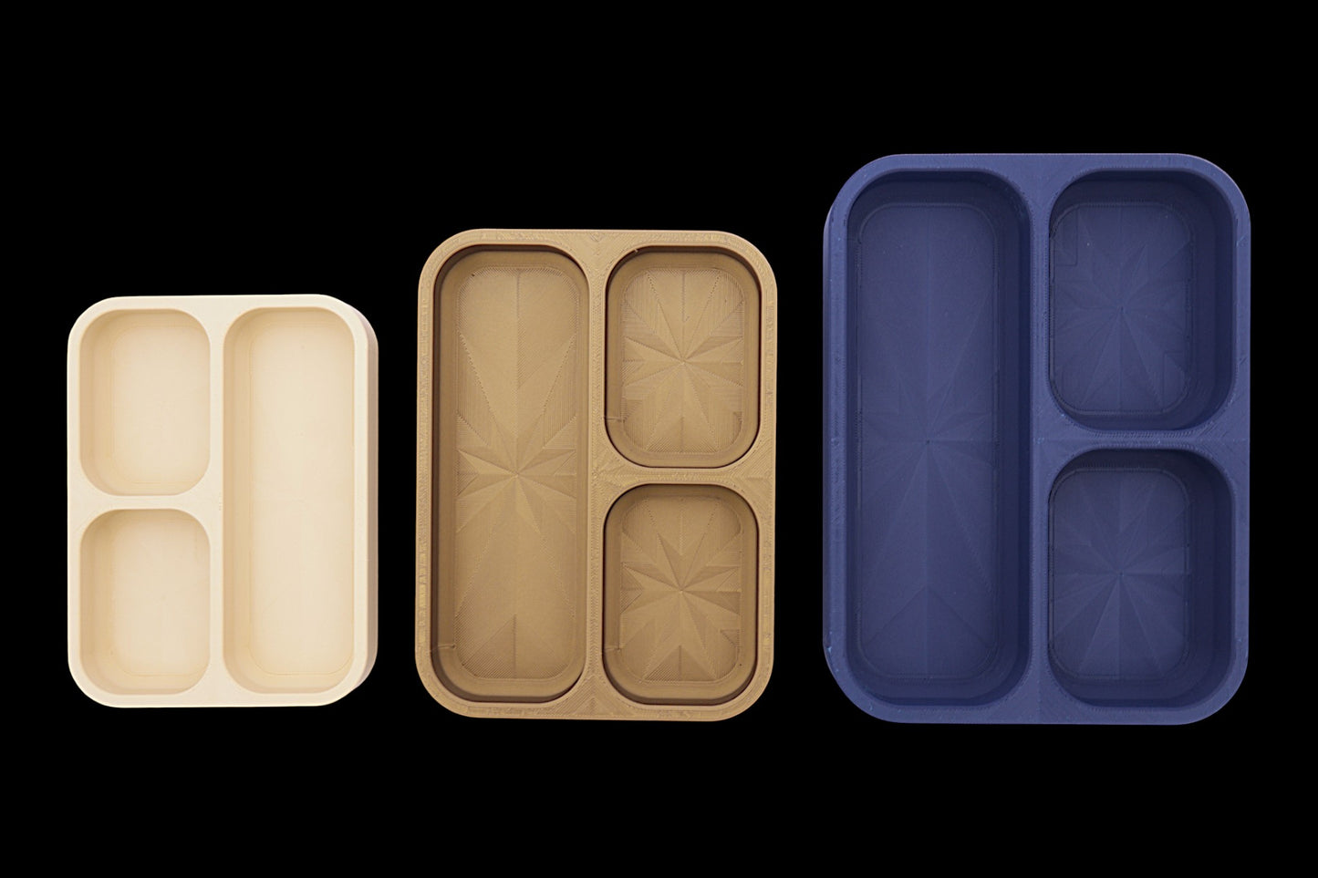Three compartmentalized trays in beige, brown, and blue on a black background