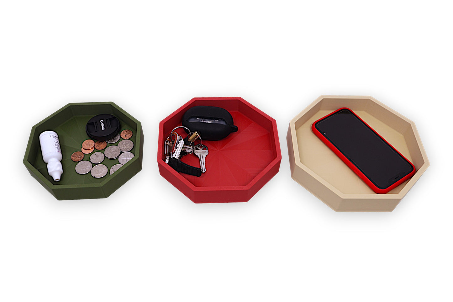 Three hexagonal trays in green, red, and beige with various items on a white background