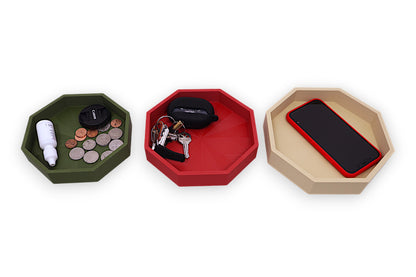 Three hexagonal trays in green, red, and beige with various items on a white background