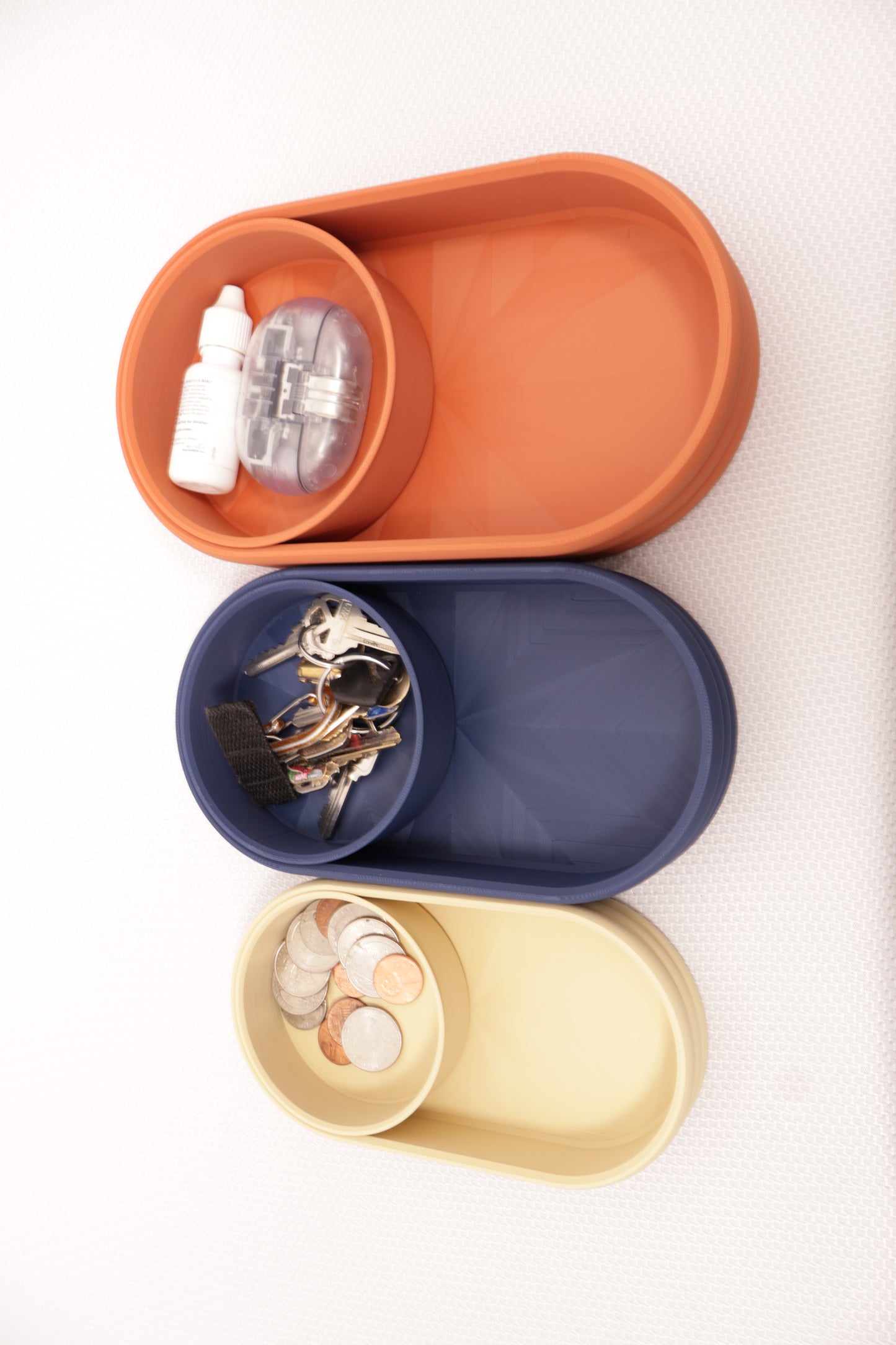 Catch-all trays – set in Tan, navy blue, and terracotta PLA, shown with coins, keys, brush, bottle, and small items