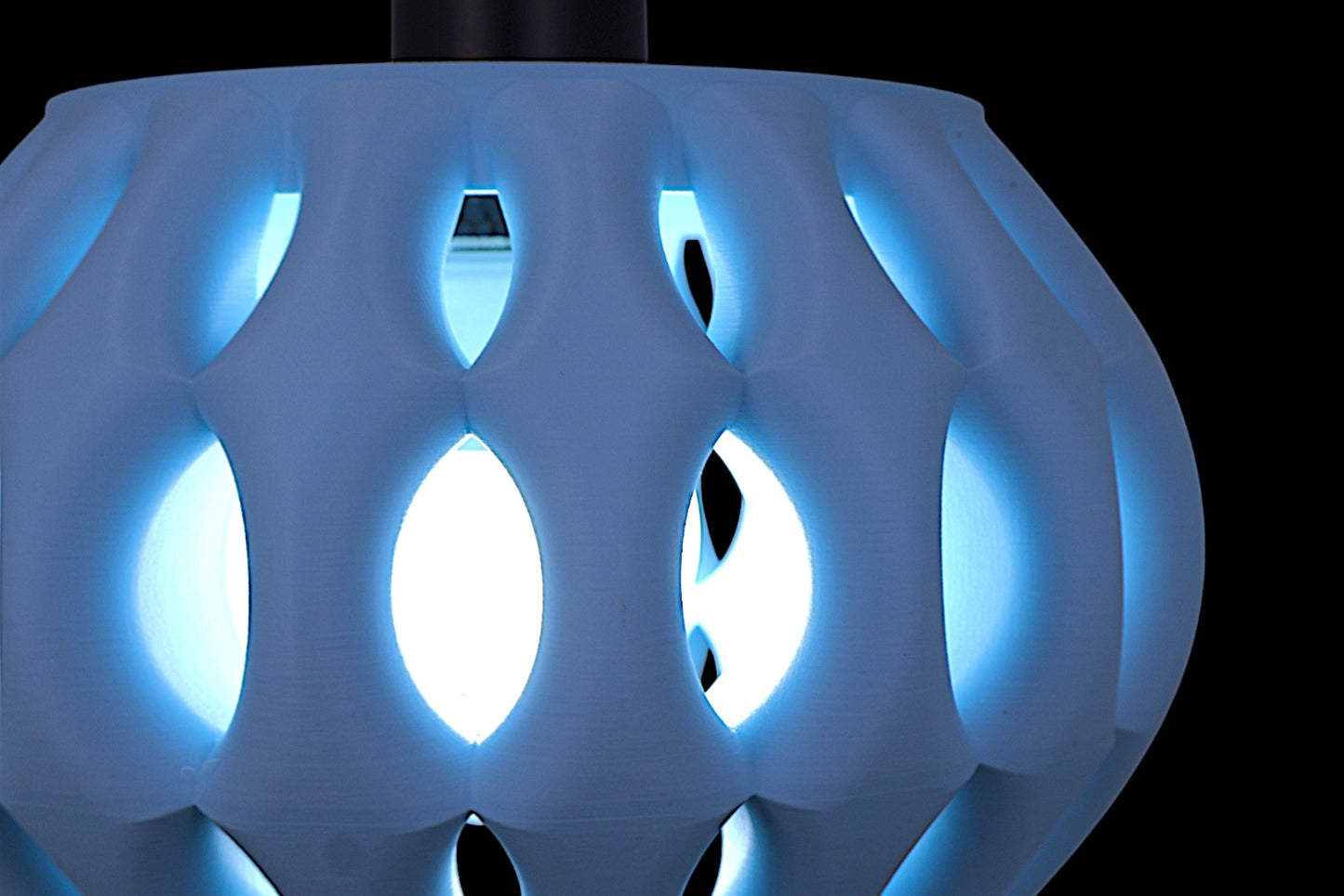 Close-up of a futuristic, blue-lit object with geometric design on a black background