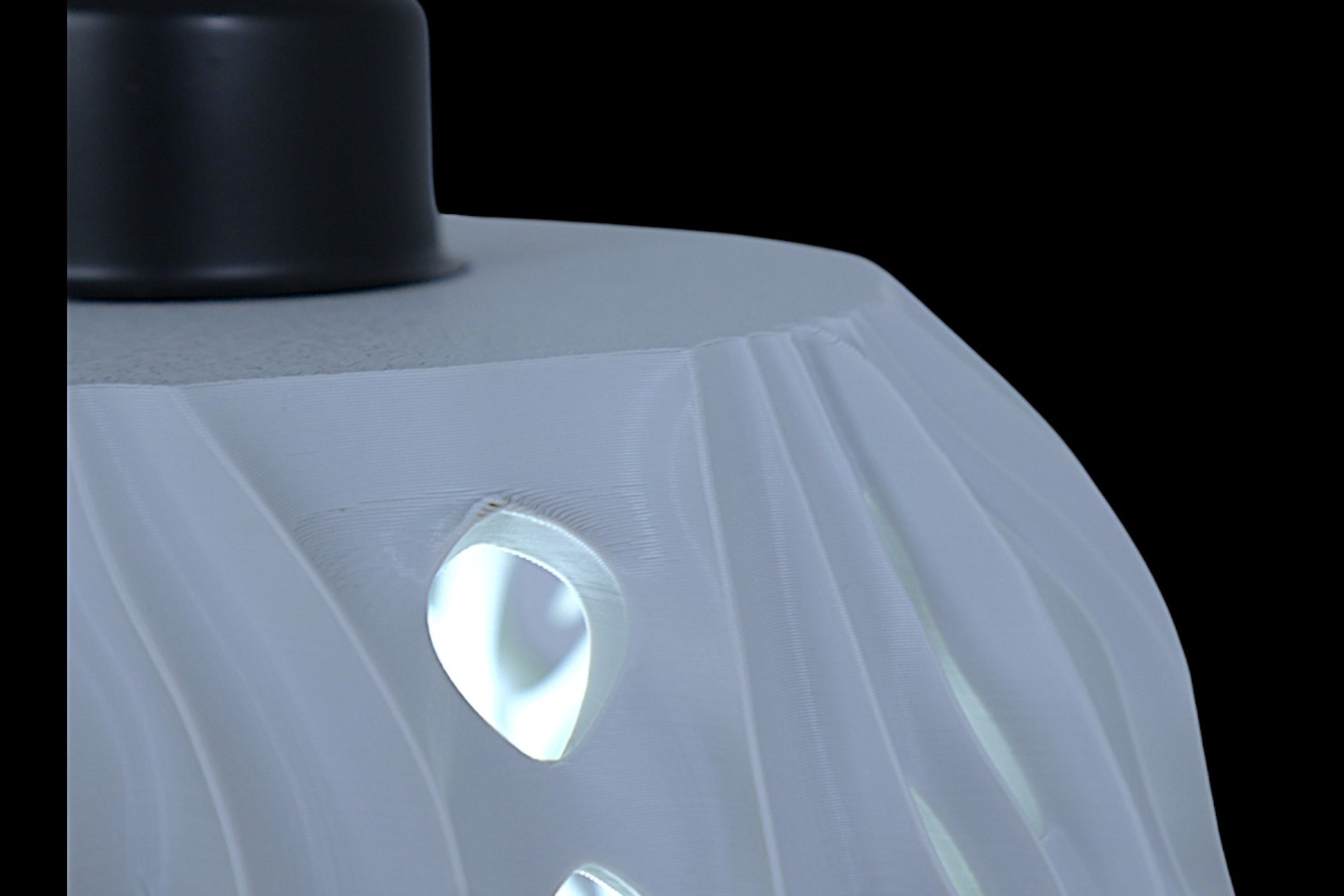 Pendant lamp – 3D printed with light gray shell and flame-inspired cutouts, glowing bulb visible through perforations
