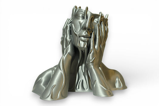 Silver 3D‑printed sculpture of a stylized human face with closed eyes and melting hands pressed against the cheeks, featuring flowing textures that resemble liquid metal