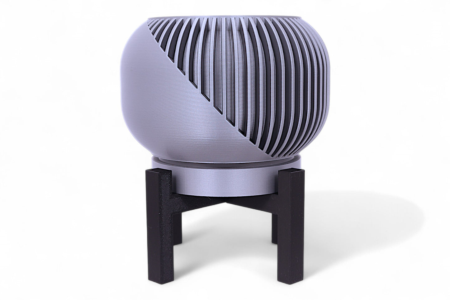 Silver planter with diagonal slatted upper half and smooth lower section on black stand