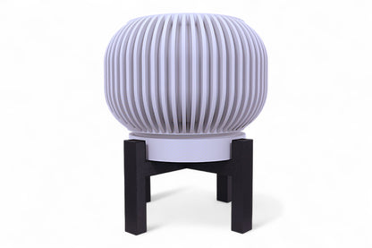 Gray planter with smooth rounded body on black four-legged stand