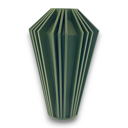 A green, geometric vase with a faceted design. The vase has a unique, angular shape with multiple vertical ridges and grooves, giving it a modern and sculptural appearance. The vase tapers slightly towards the bottom and has a flat top opening.