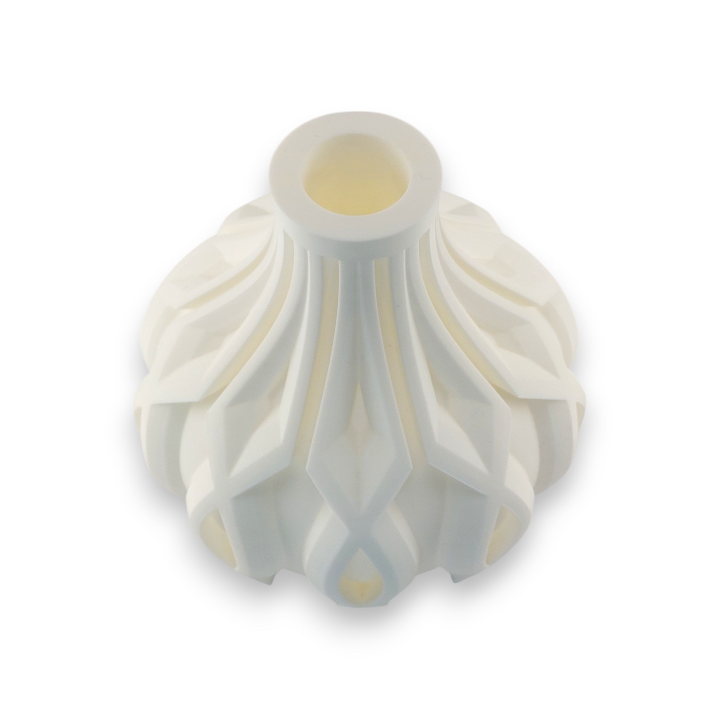 A white, intricately designed vase with a narrow opening at the top. The vase features a geometric pattern with raised, diamond-shaped elements and curved lines that create a textured, three-dimensional appearance. The design is symmetrical and appears to be inspired by modern or contemporary art styles. The vase's unique and detailed design makes it an interesting piece for decorative purposes.